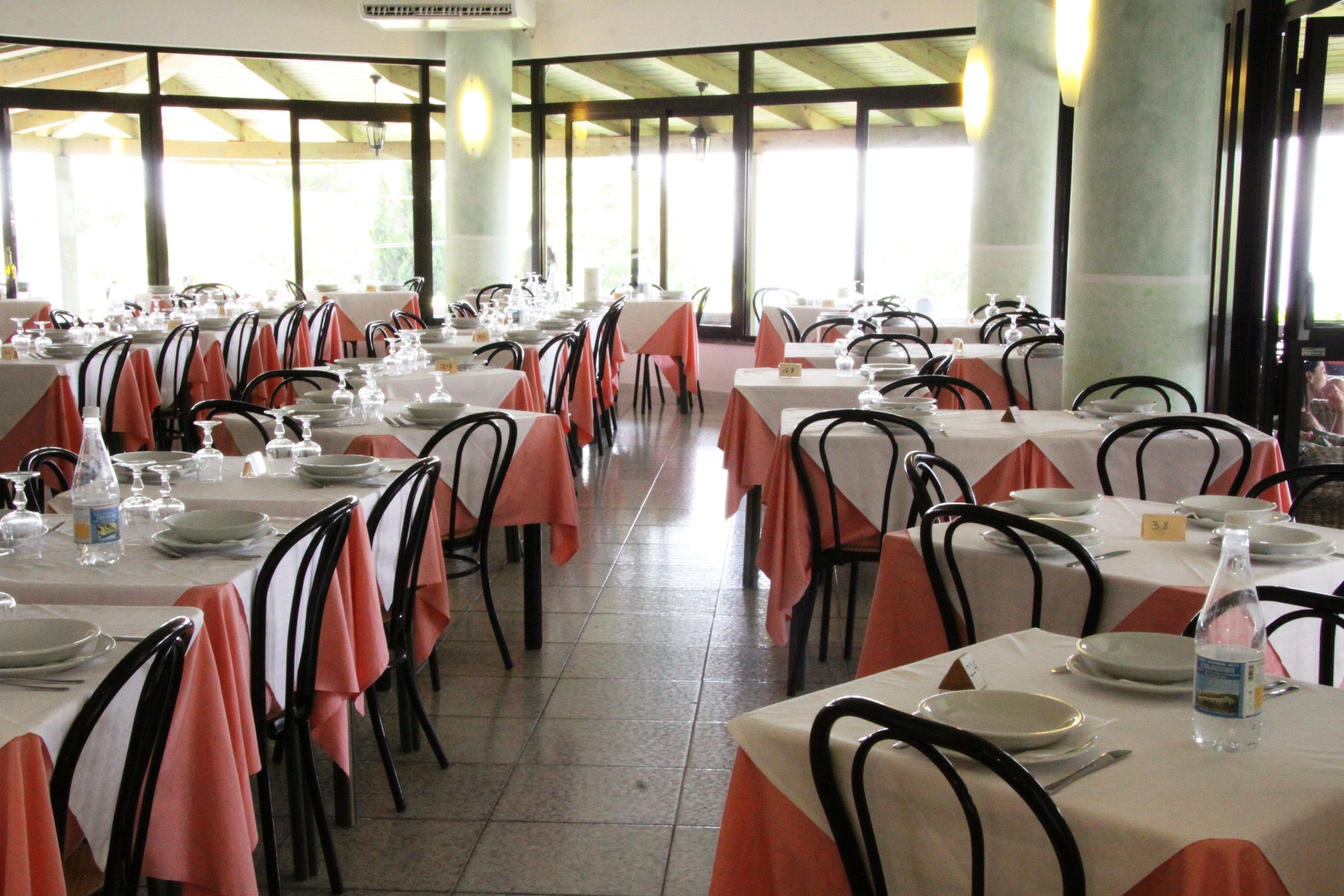 Un restaurante con varias mesas dispuestas para comer, con manteles blancos y sillas negras.