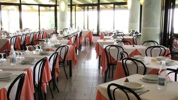 Un restaurante con varias mesas dispuestas para comer, con manteles blancos y sillas negras.