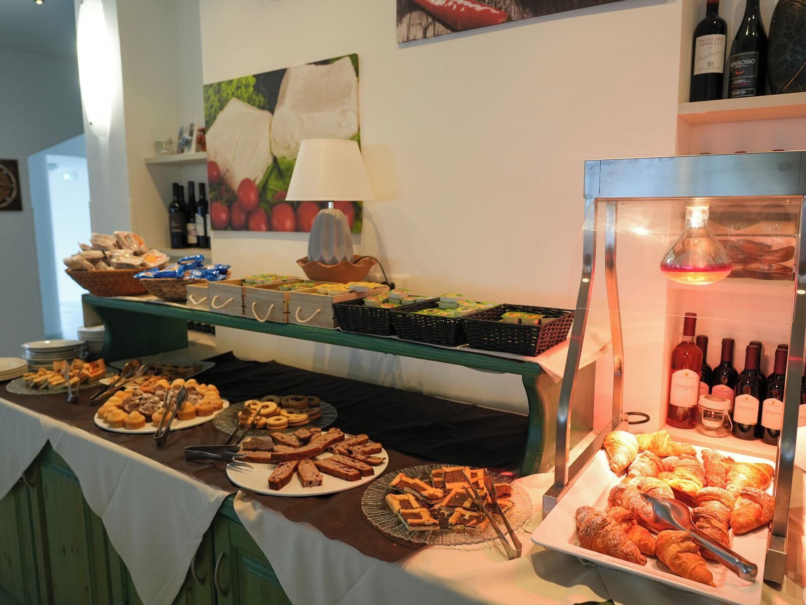 A buffet with various pastries, a wine cooler, and a fruit display.