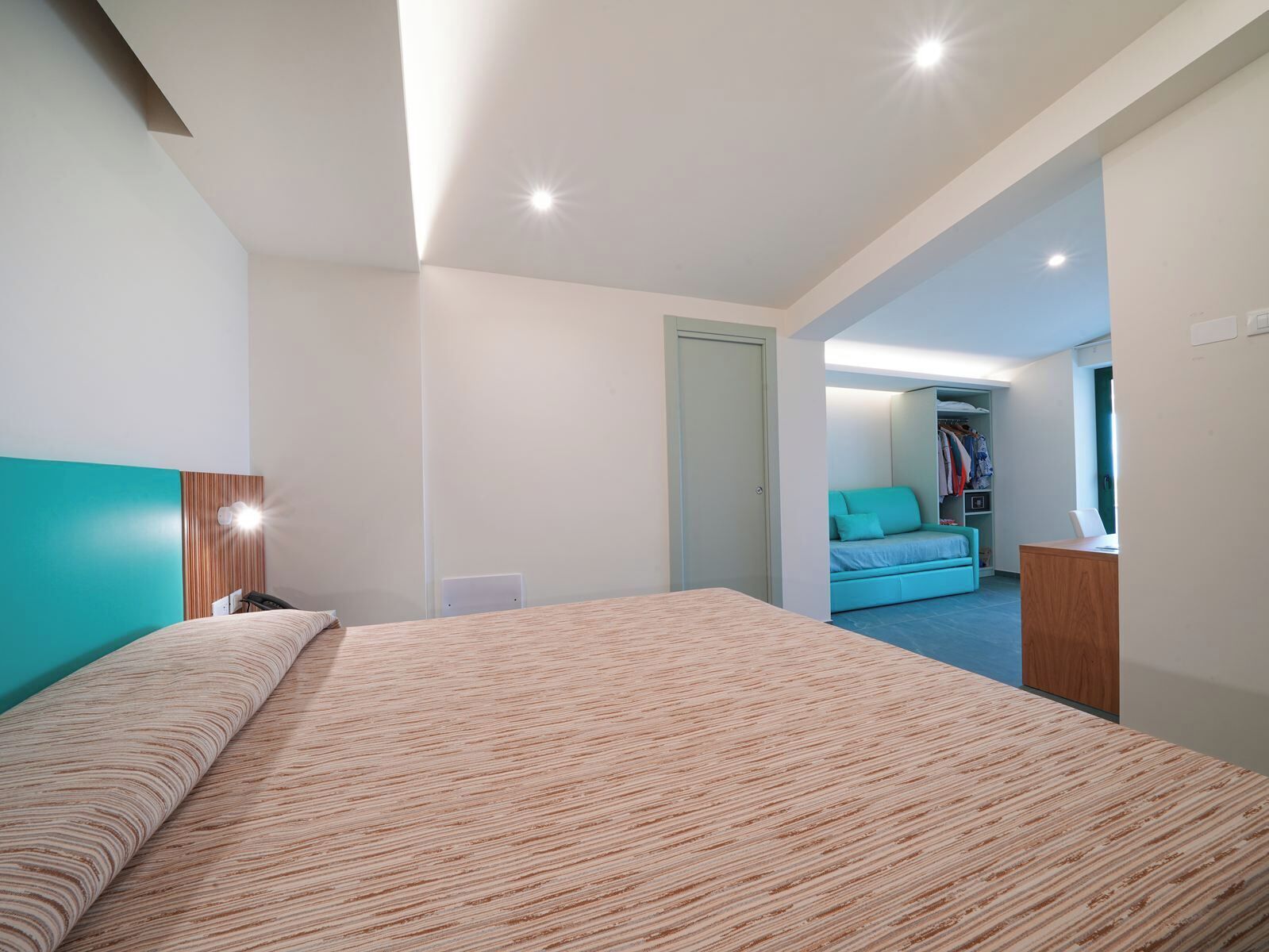 Une chambre moderne avec un grand lit, un bureau et un dressing.