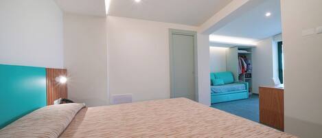 Une chambre moderne avec un grand lit, un bureau et un dressing.