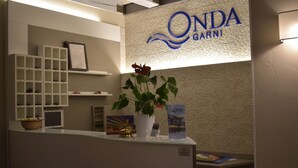Ein Empfangsschalter mit einer Pflanze, einem gerahmten Bild und einem Schild mit der Aufschrift 'ONDA GARNI'.