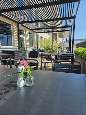 Un espacio al aire libre con patio, una mesa, sillas y una estructura de pérgola.