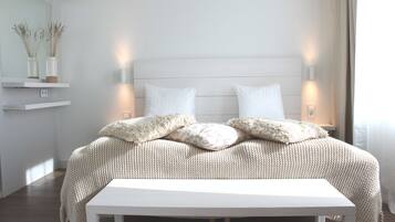 A neatly made bed with a white headboard, two bedside lamps, and a bedside table.