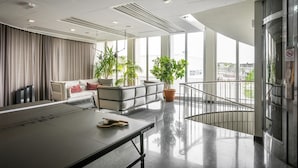 A modern hotel lobby with a ping pong table, seating area, potted plants, and a view of the city through large windows. - Best Western Plus Sthlm Bromma (Bromma)