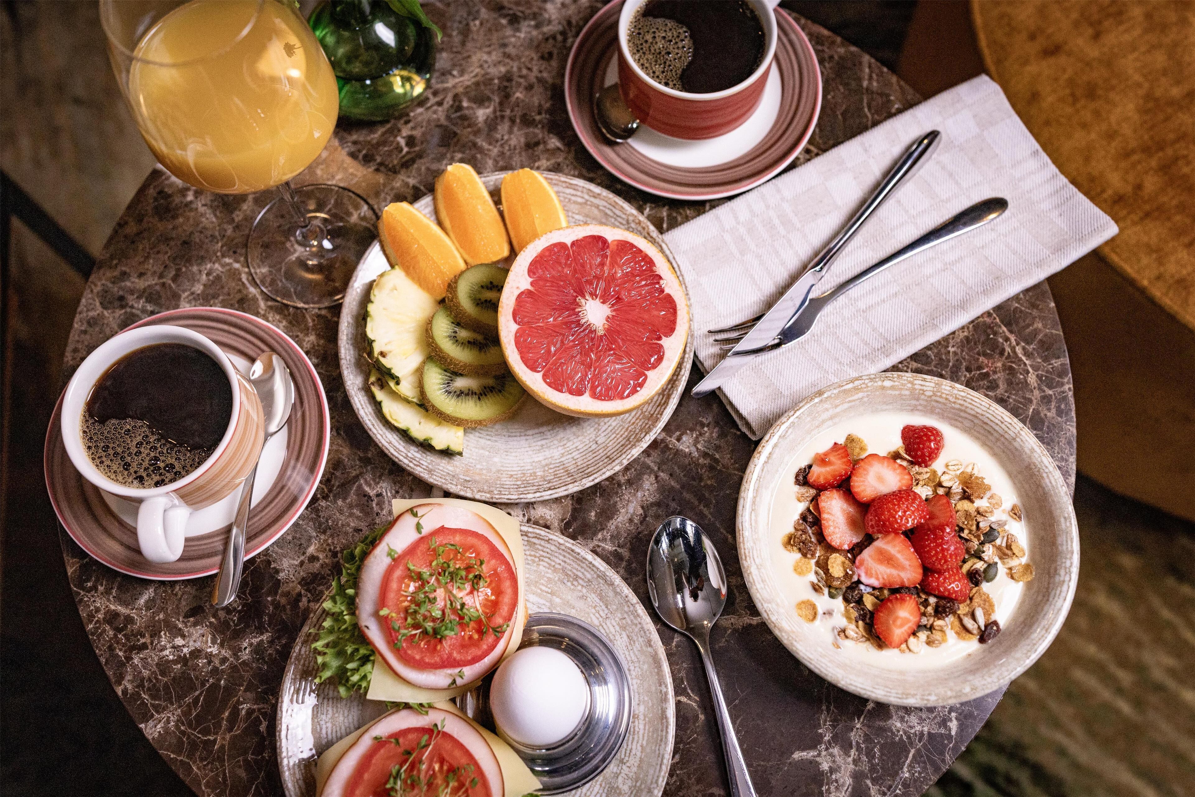 A table with breakfast items including toast, fruit, yogurt, and coffee.
