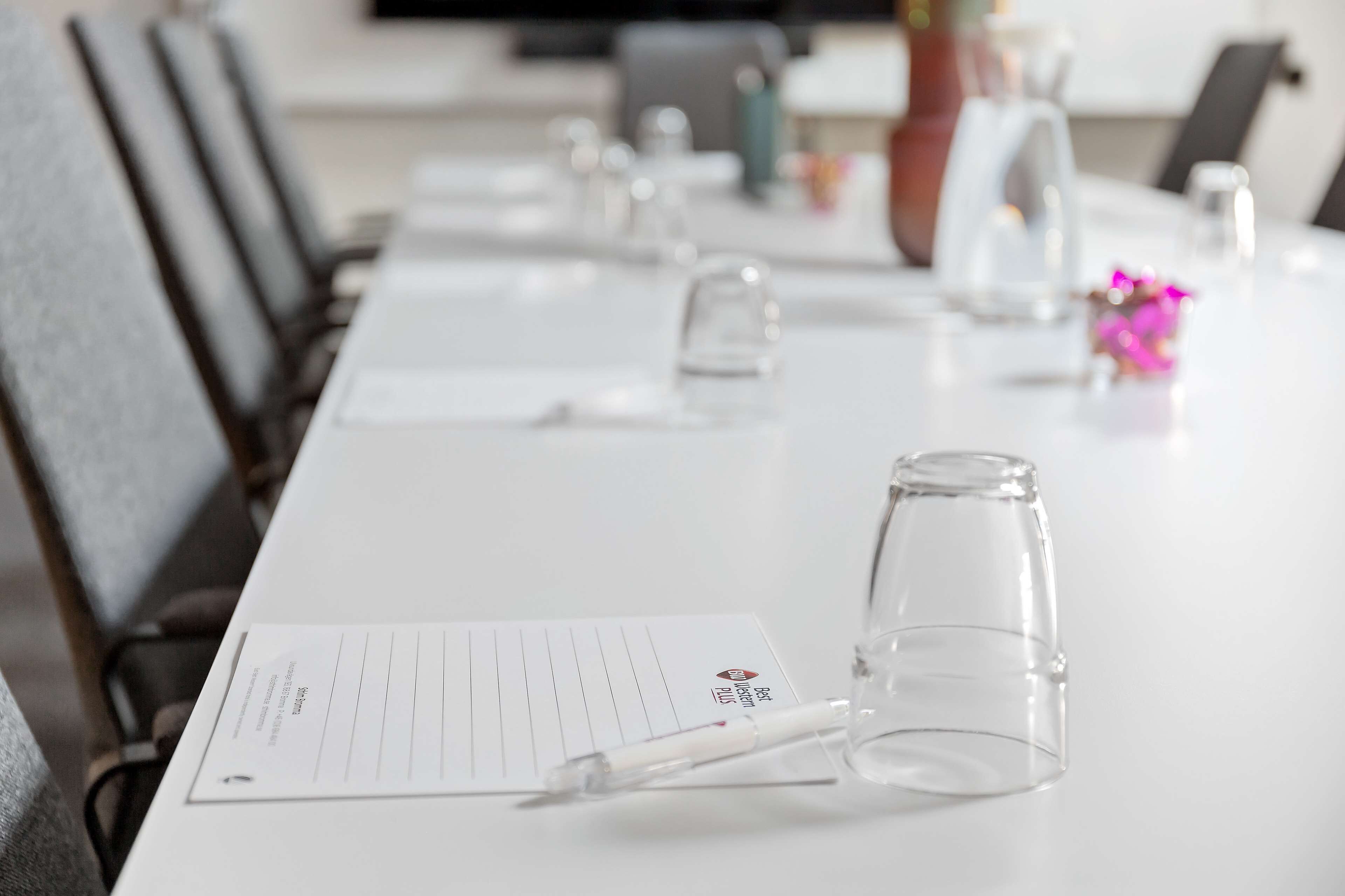 Ett konferensbord med ett anteckningsblock, en penna och ett glas.