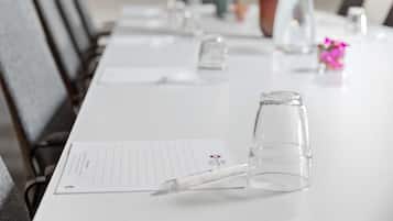 Ett konferensbord med ett anteckningsblock, en penna och ett glas.