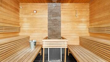 Una sauna con bancos de madera y una pared de piedra en el centro.