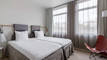 Una habitación de hotel con una cama grande, una silla y una ventana con cortinas.