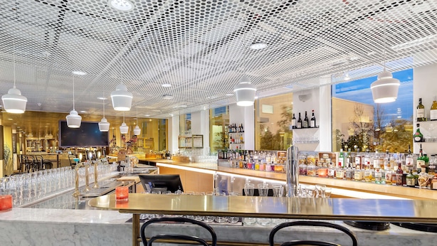 A modern bar area with a marble countertop, black bar stools, and a ceiling with a perforated pattern. - Best Western Plus Sthlm Bromma (Bromma)