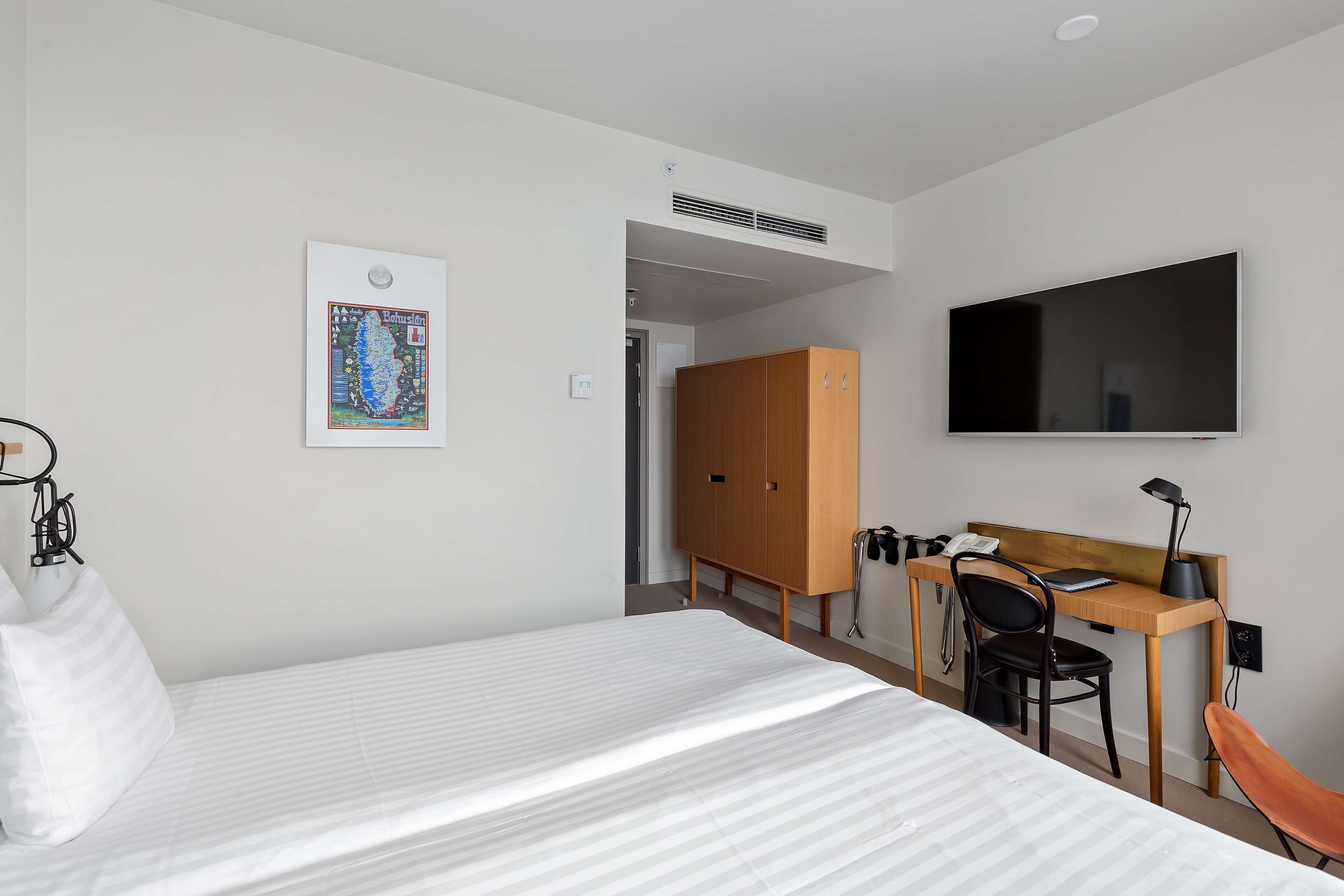 Ett hotellrum med en säng, ett skrivbord, en stol, en tv och en garderob.