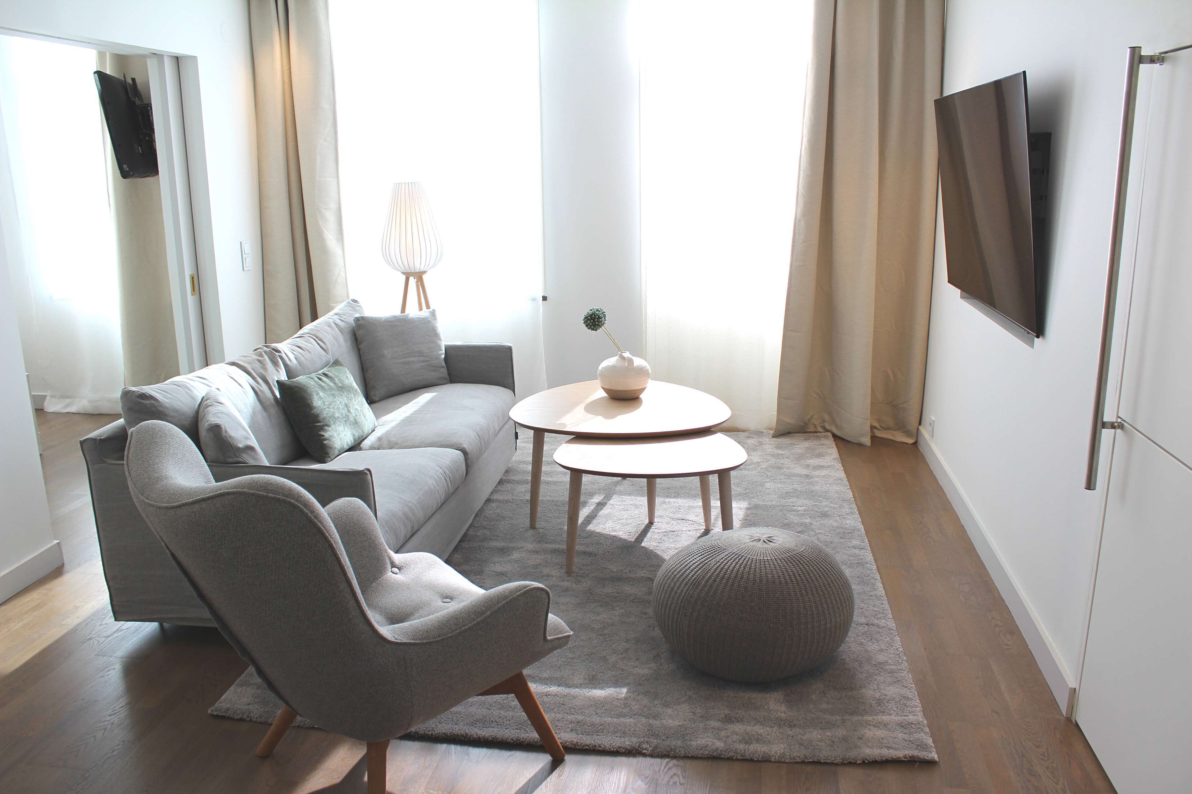 A modern living room with a grey sofa, a round coffee table, and a grey armchair.
