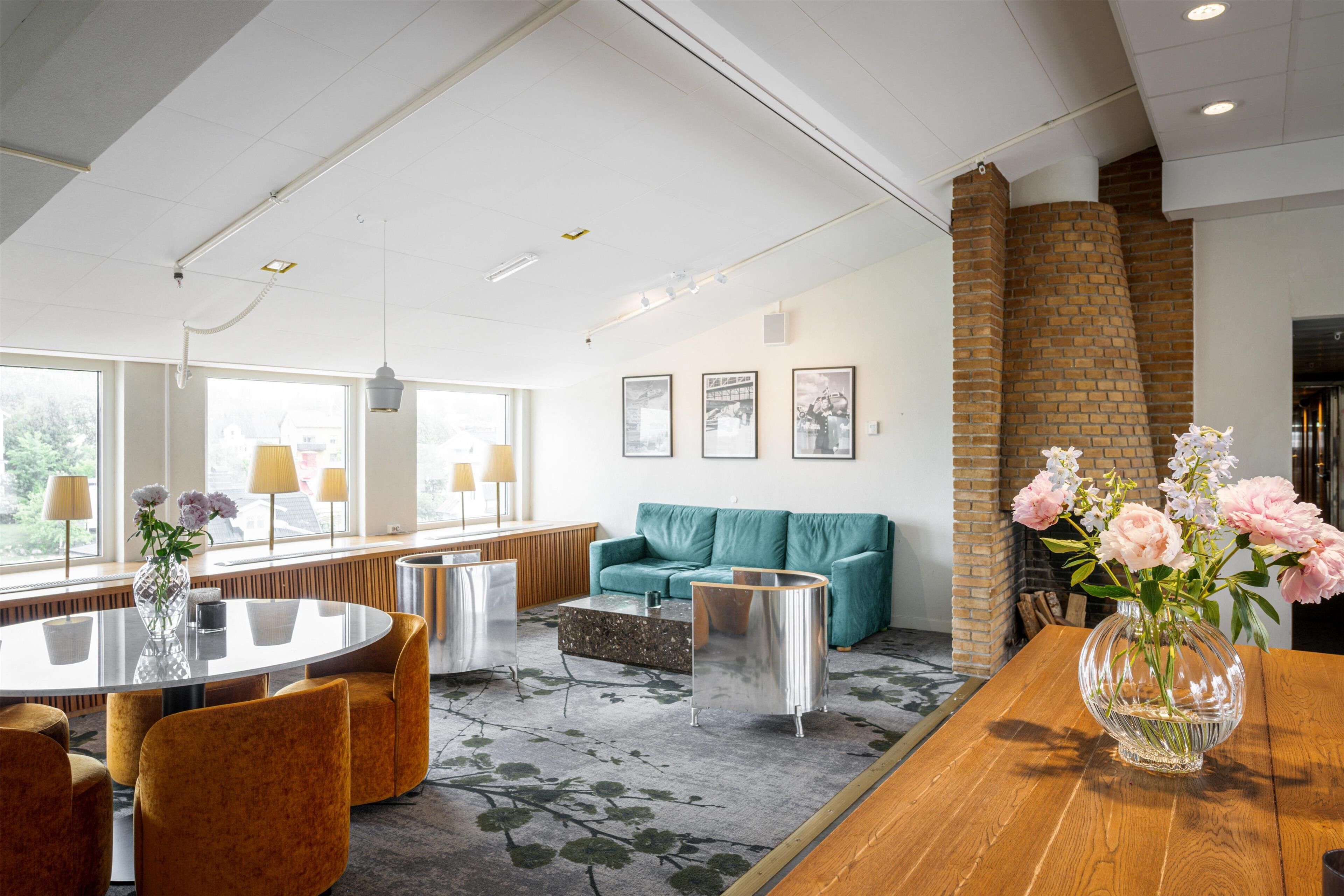 A modern hotel lobby with a round table, sofas, and a brick fireplace.