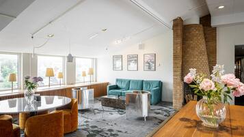 A modern hotel lobby with a round table, sofas, and a brick fireplace.