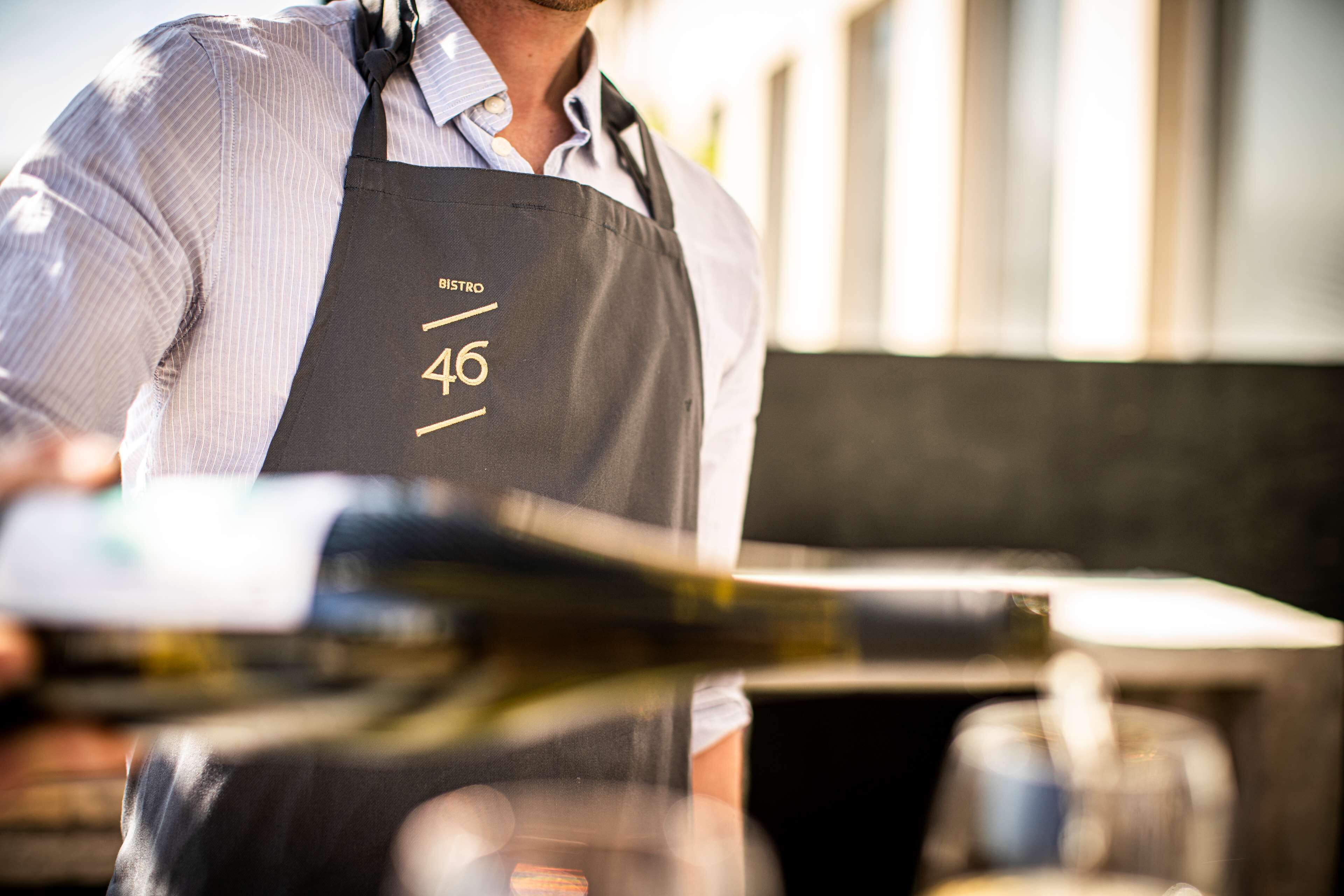 A person wearing a black apron with the number 46 and the word "BISTRO" on it.
