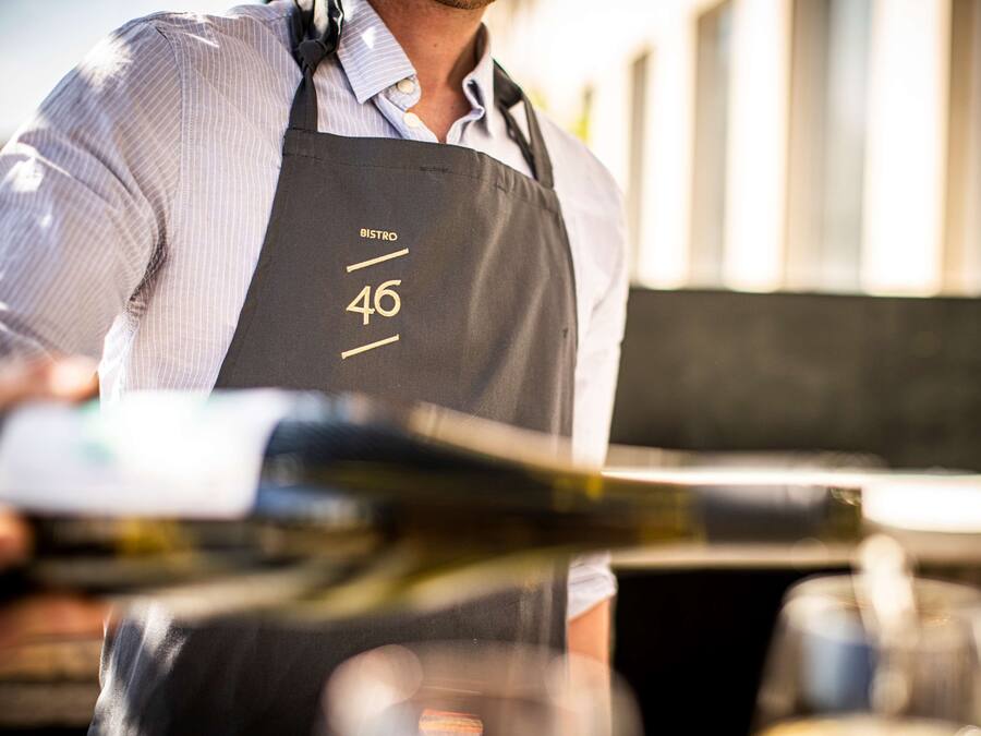 A person wearing a black apron with the number 46 and the word "BISTRO" on it.