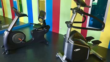 Duas bicicletas ergométricas em uma academia com paredes coloridas.