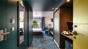 Une chambre d’hôtel avec un lit, un bureau et une chaise, une télévision et une vue sur l’extérieur.