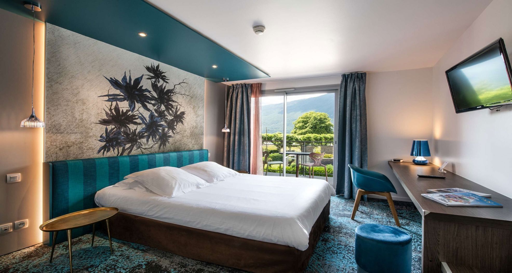 Een hotelkamer met een bed, een bureau, een stoel, een televisie en uitzicht op de omgeving.