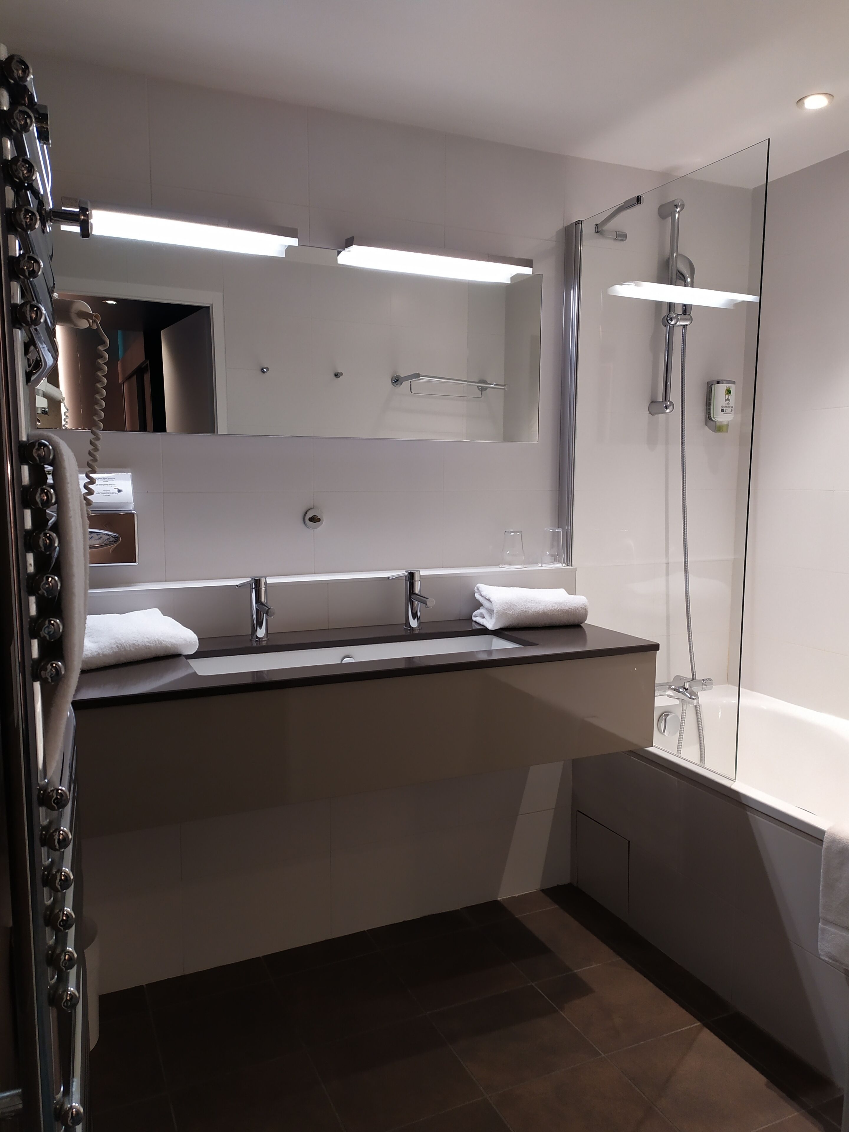 Un baño moderno con un espejo grande, dos lavamanos, ducha y bañera.