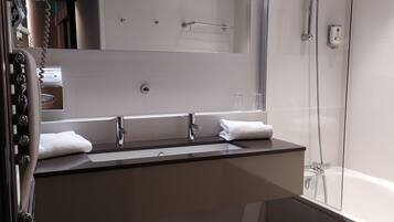 Un baño moderno con un espejo grande, dos lavamanos, ducha y bañera.