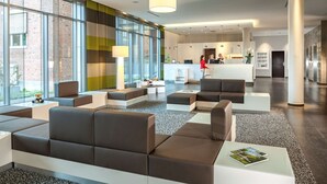 Een moderne hotellobby met zitgedeeltes, een receptiebalie en grote ramen.
