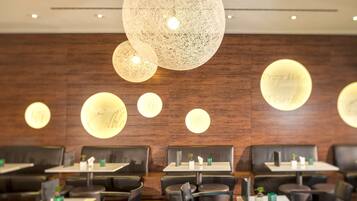A restaurant interior with wooden walls, multiple tables, and chairs.