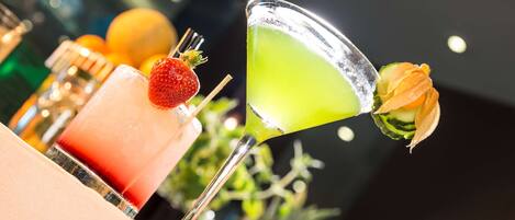 Eine Bar mit verschiedenen Getränken, darunter ein Martini und ein Cocktail mit Erdbeere.