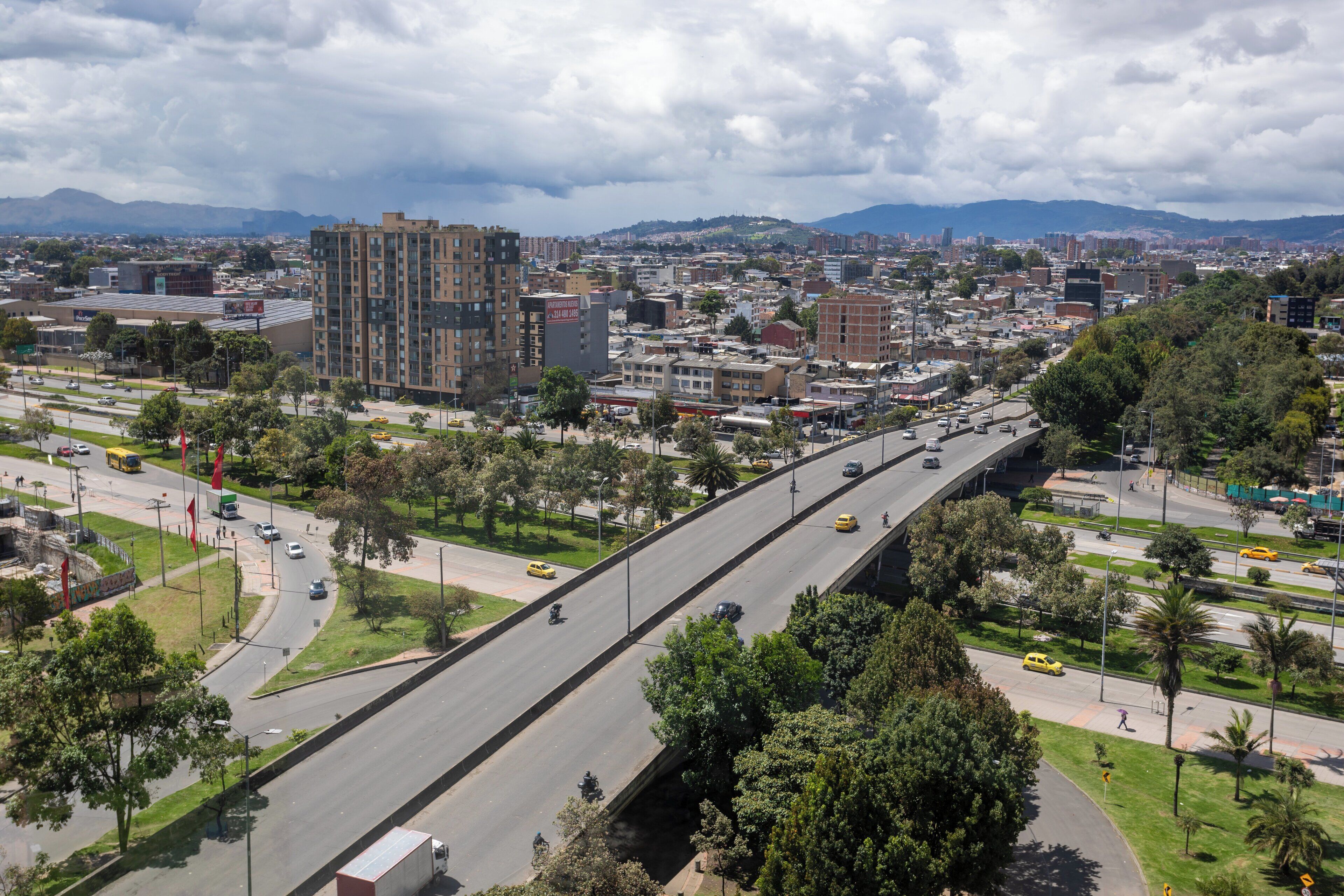 Un paisaje urbano con un edificio alto, calles anchas y zonas verdes circundantes.