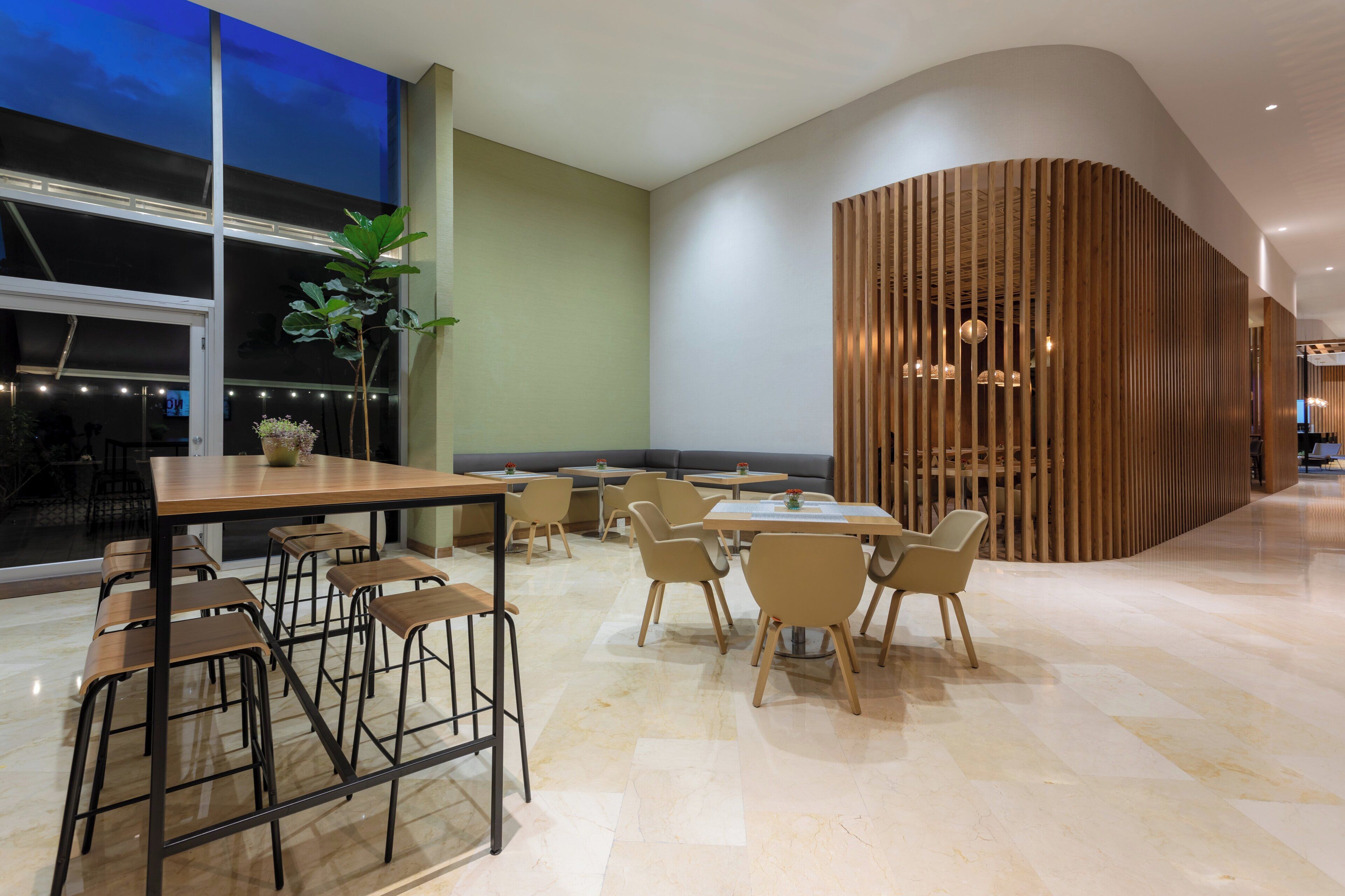 Un ristorante moderno con tavoli e sedie alti, una grande vetrata e un pannello decorativo in legno.