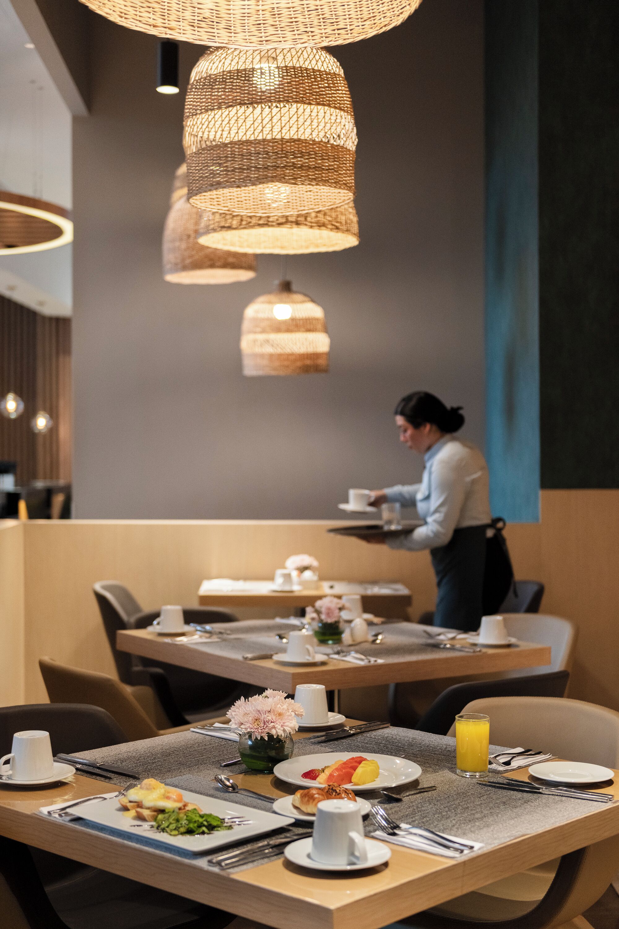 A dining area with tables set for breakfast, including plates with food and drinks.