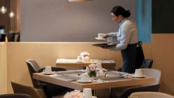 A dining area with tables set for breakfast, including plates with food and drinks.
