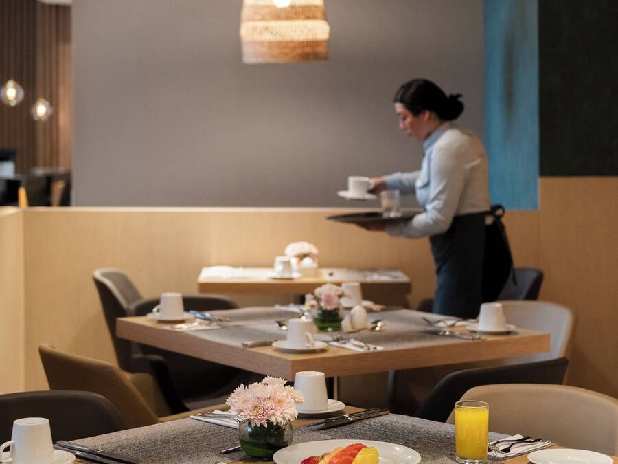 A dining area with tables set for breakfast, including plates with food and drinks.
