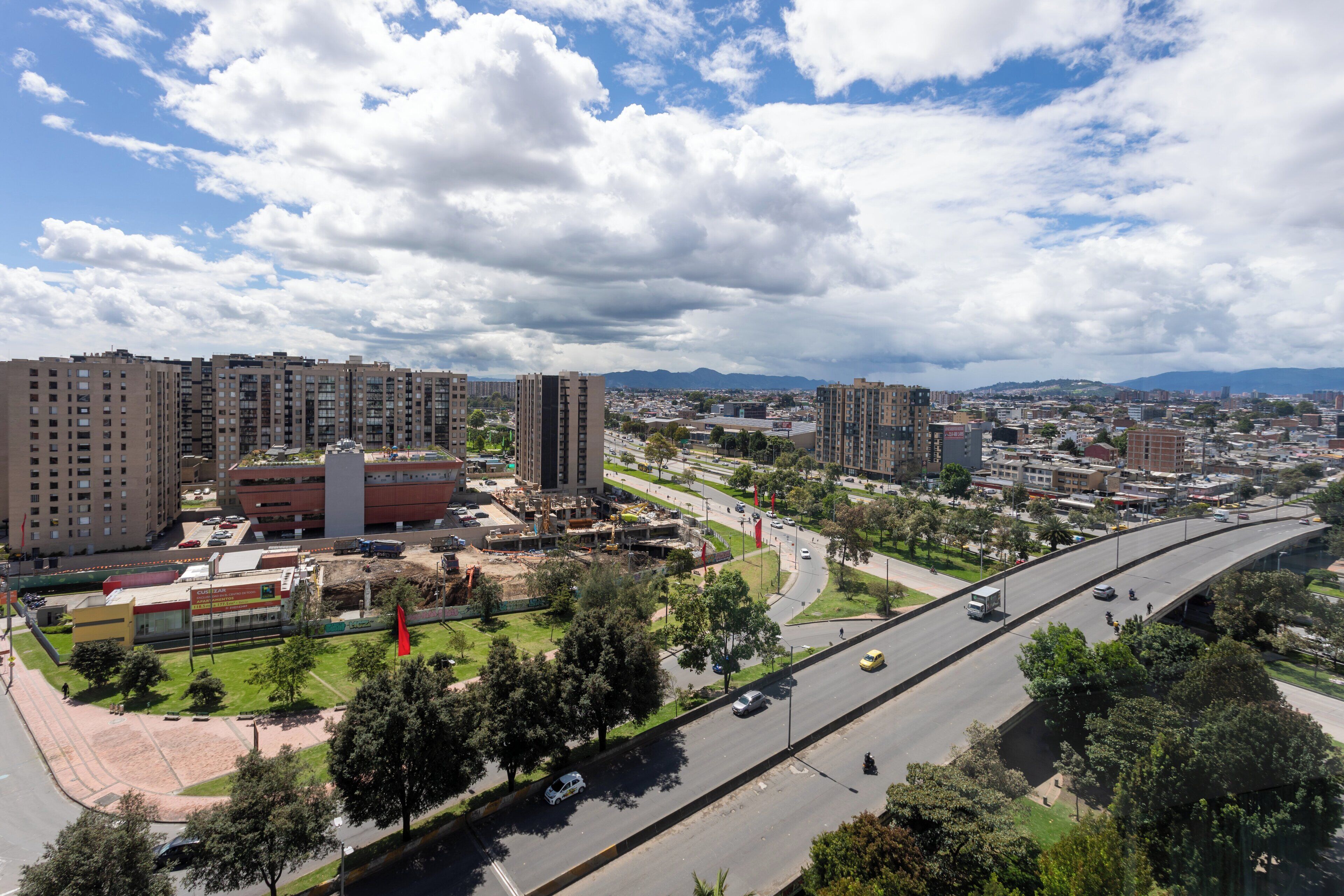 A cityscape with high-rise buildings, a highway, and a river.
