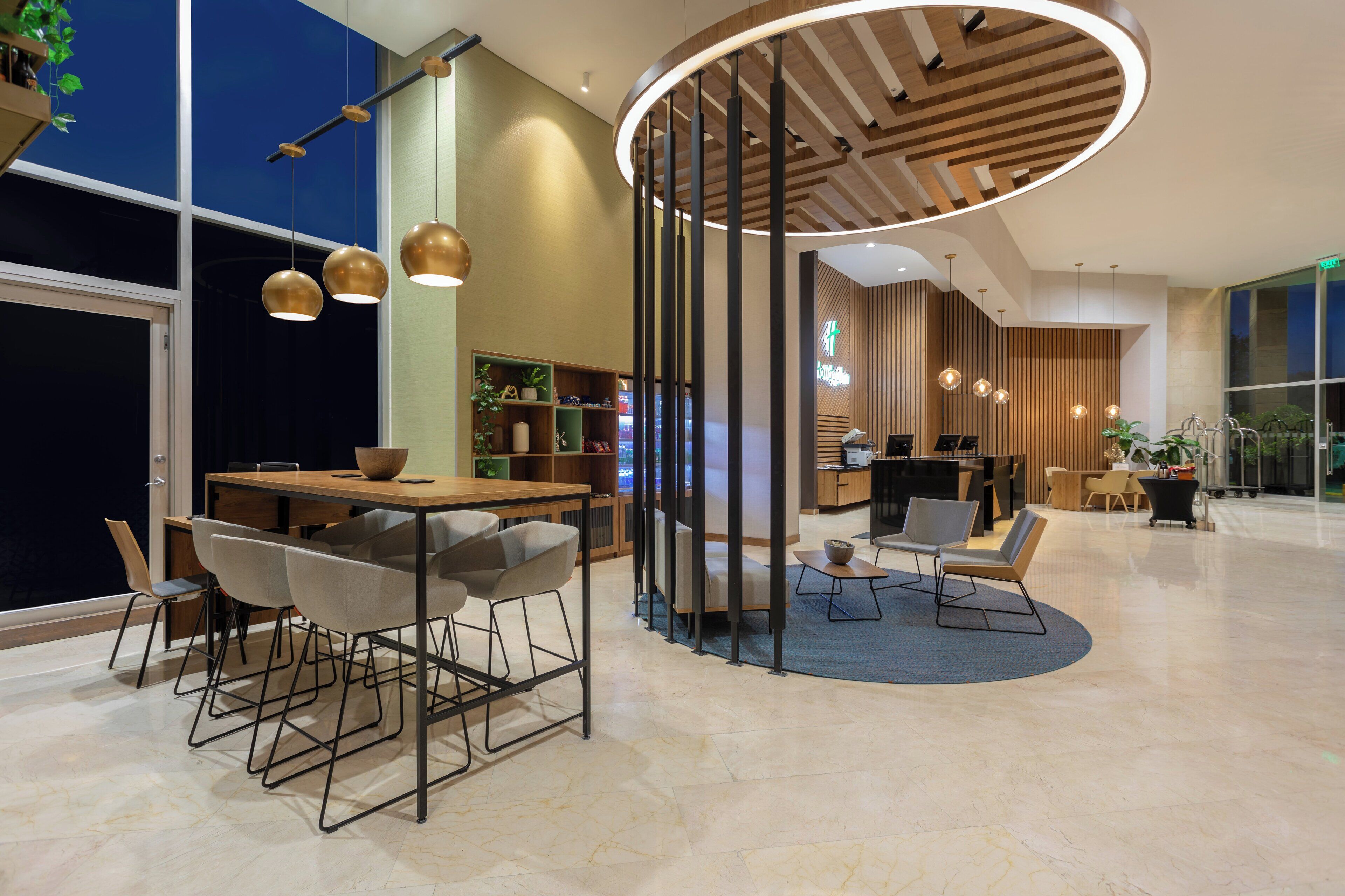 A modern interior with a wooden dining area, a reception desk, and a circular seating area.