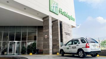 L’entrée d’un hôtel, avec une enseigne « Holiday Inn », une voiture garée devant et un panneau « stationnement interdit » sur le mur.