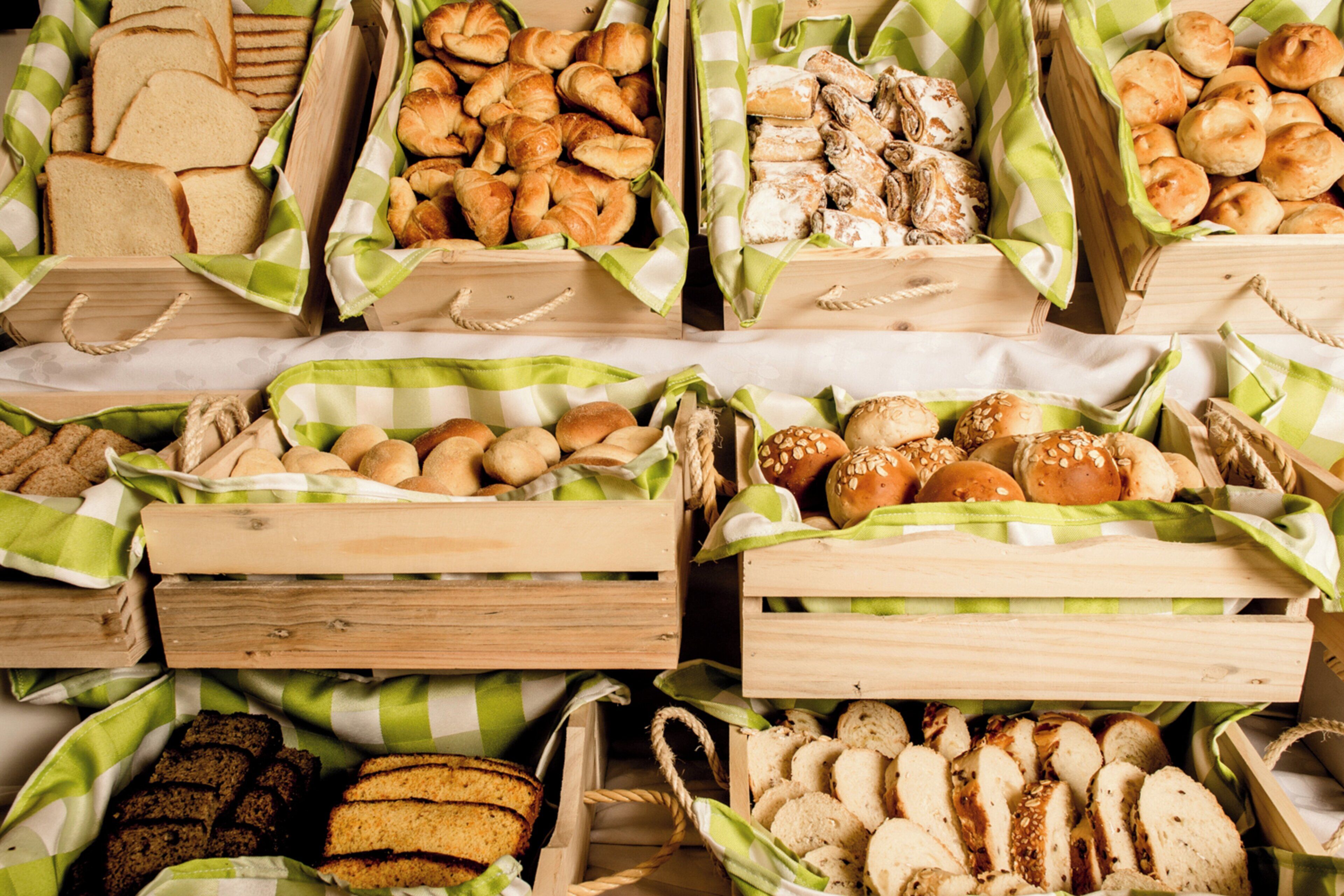 Une variété de produits de boulangerie présentés dans des caisses en bois recouvertes de nappes à carreaux verts et blancs.