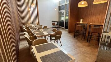 Ein modernes Restaurant mit Holzvertäfelung, mehreren Tischen und hängenden Pendelleuchten.