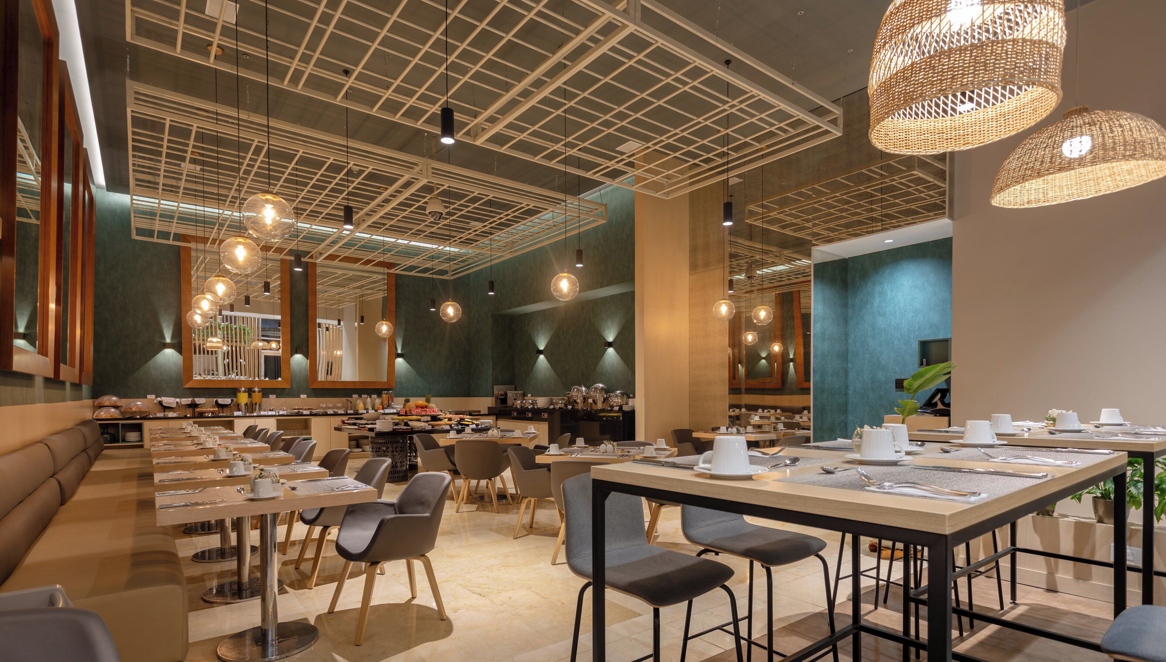 A modern restaurant with high ceilings, pendant lighting, and a variety of seating arrangements including tables and booths.