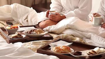 Ett hotellrum med en säng, ett frukostbricka med bakverk och en kopp kaffe.