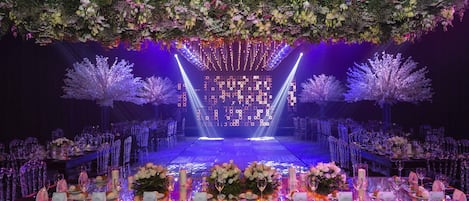 Un escenario con fondo floral y disposición de asientos para un evento.