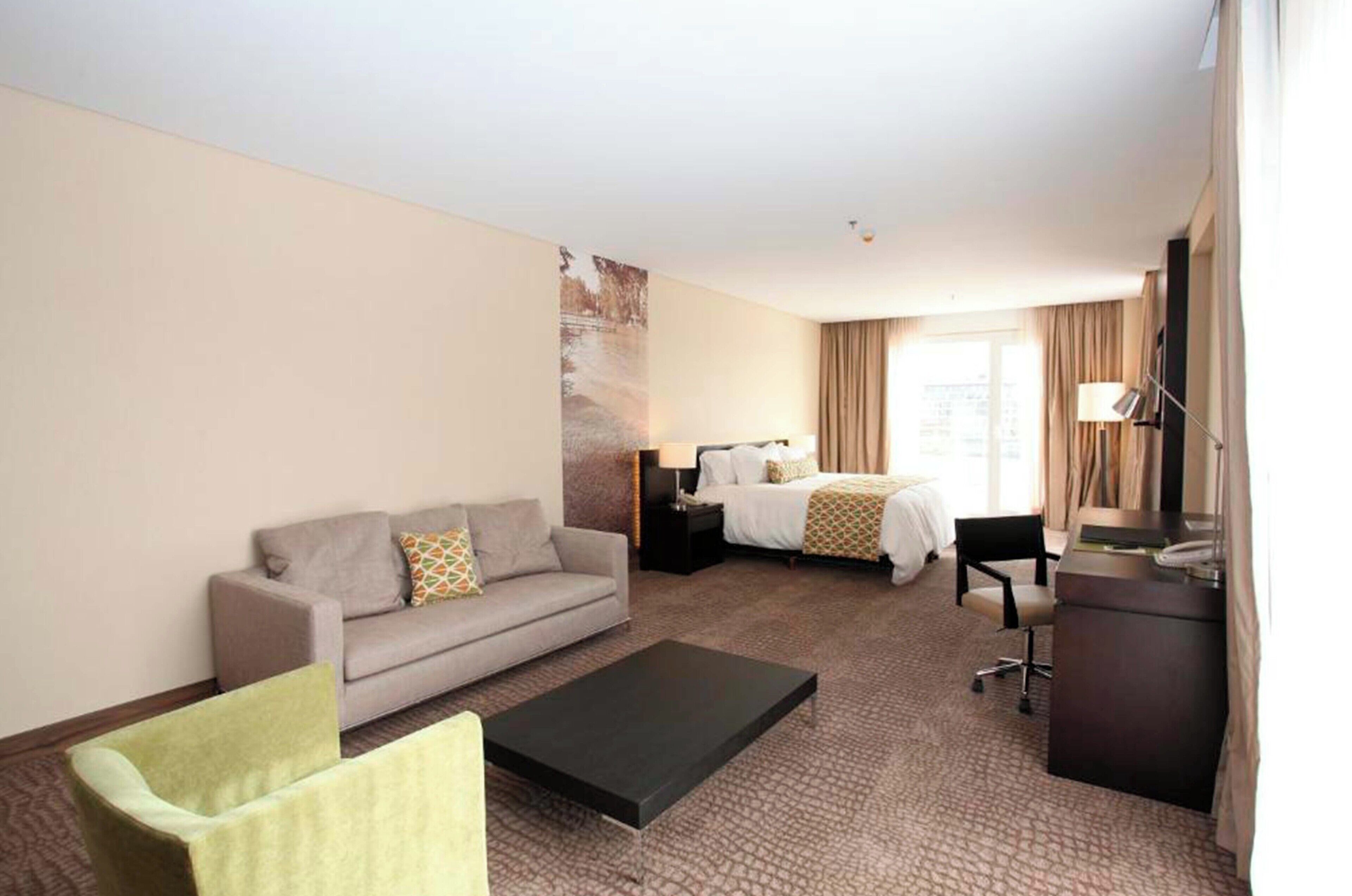 Una habitación de hotel con sofá, cama, escritorio y mesa de centro.