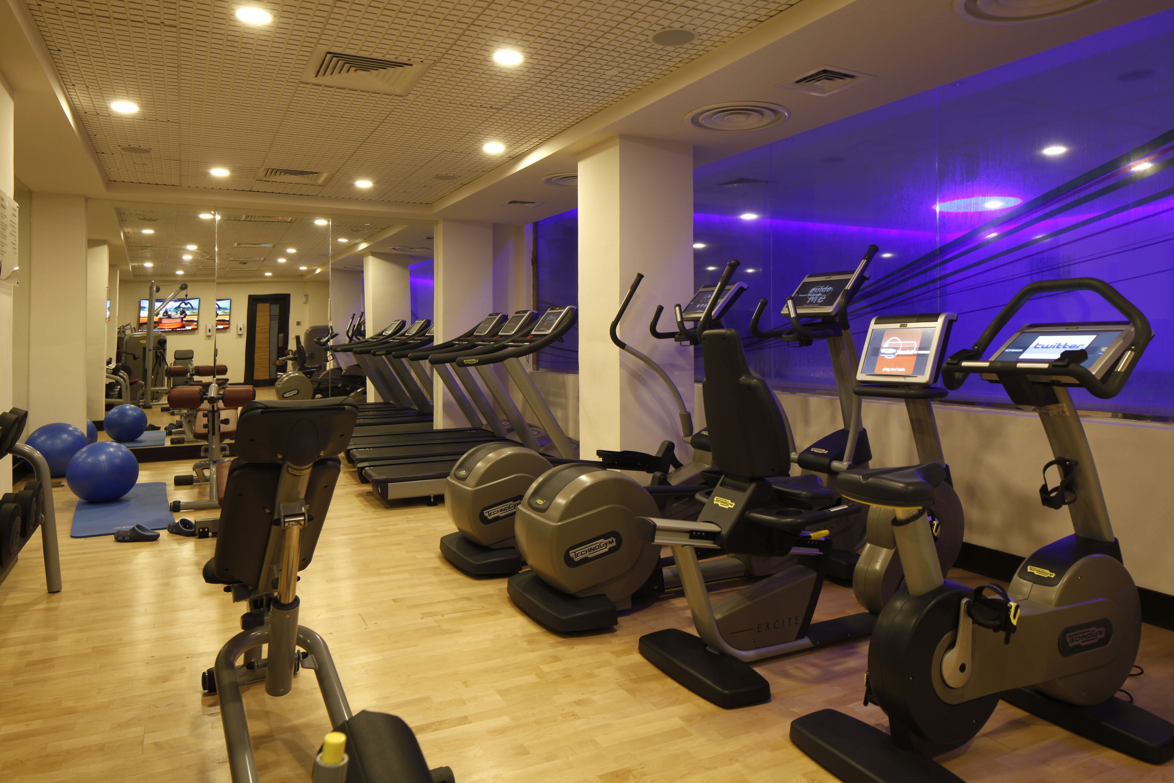 Uma academia com esteiras, elípticos e bolas de exercício.