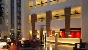 A spacious lobby with a reception desk, seating areas, and a modern architectural design.