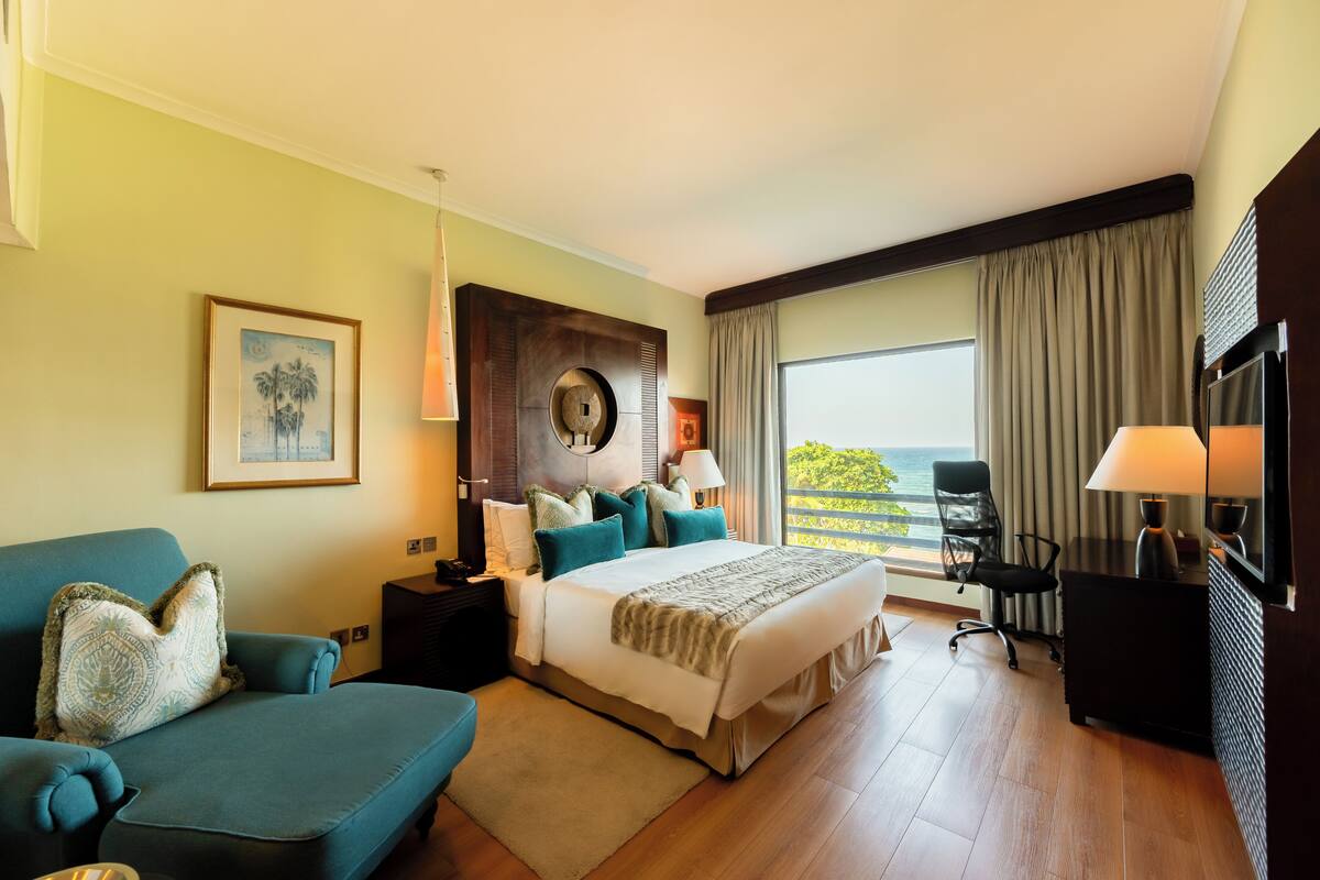 Une chambre d’hôtel équipée d’un lit, d’un canapé, d’un bureau, d’une télévision et offrant une vue sur l’extérieur.