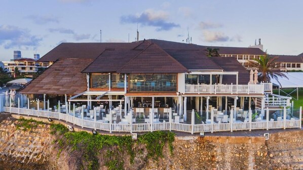 Un hotel frente a la playa con un amplio balcón, varios niveles y vistas al océano.