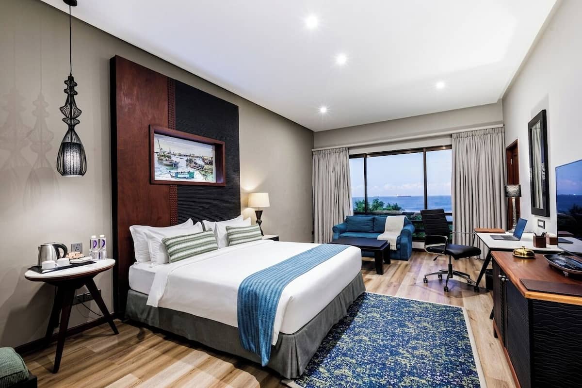 Une chambre d’hôtel équipée d’un lit, d’un bureau, d’une chaise et d’une grande fenêtre donnant sur un beau paysage.