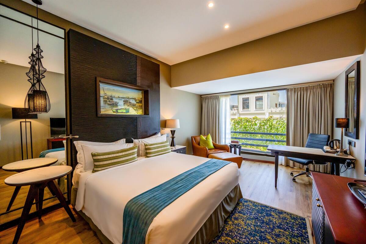 Une chambre d’hôtel avec un lit, un bureau, une chaise et une vue sur l’extérieur.