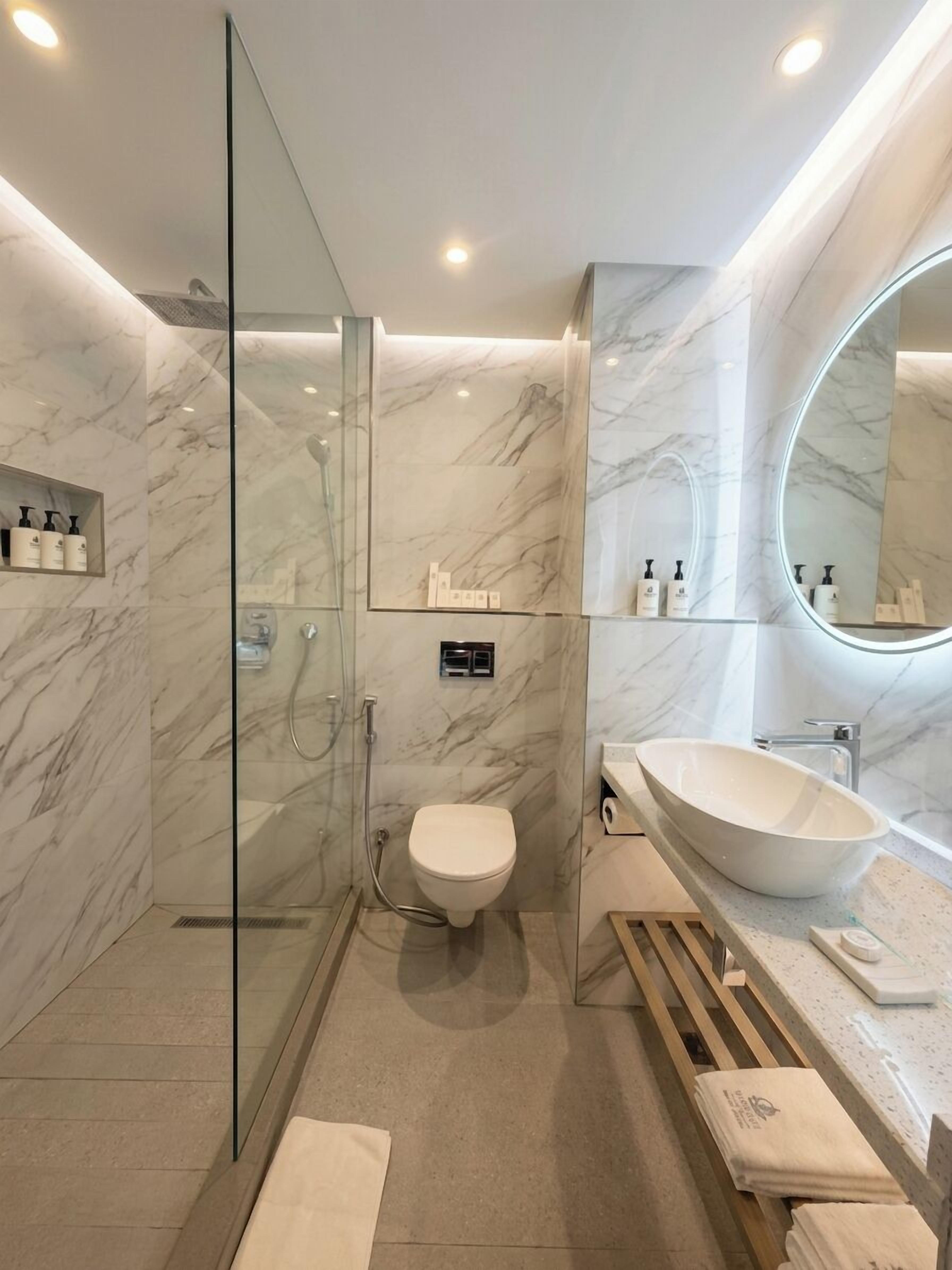 A modern bathroom with a glass-enclosed shower, a freestanding sink, and a large mirror.